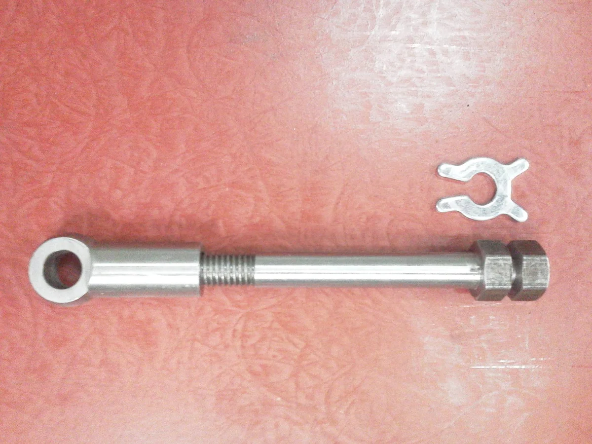 Long threaded clamp bolt with forked clamp piece on a workshop surface
