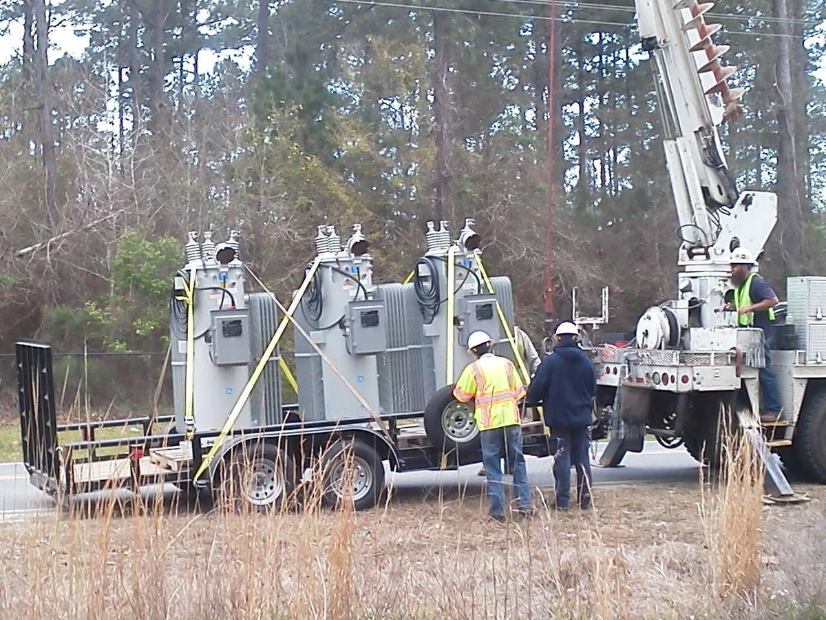 Three voltage regulators staged on a trailer with the line crew